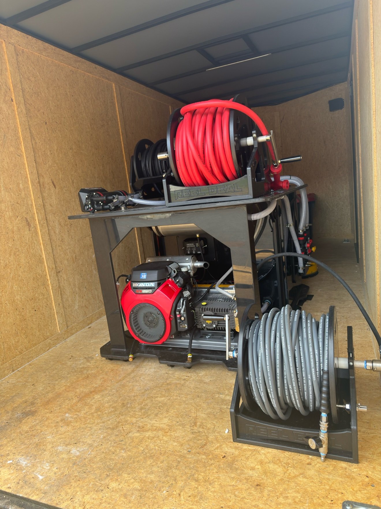 Blackrock's SESW softwash skid inside the trailer — Honda GX690 engine under stacked Reel Deal hose reels with red softwash hose and a high-pressure hose reel