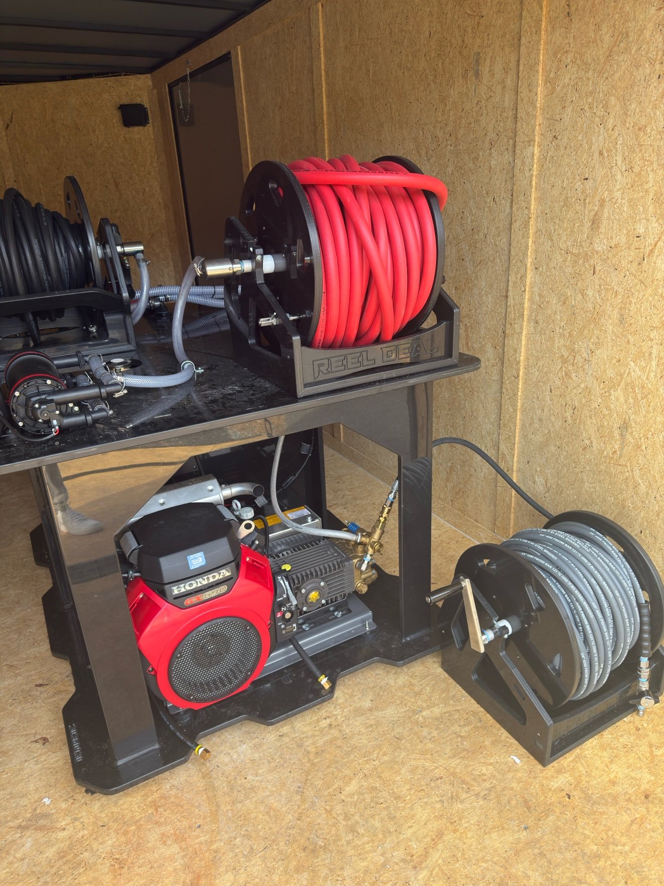 Side view of Blackrock's Honda-powered softwash skid — red softwash hose reel on top, pump and plumbing below, high-pressure reel alongside